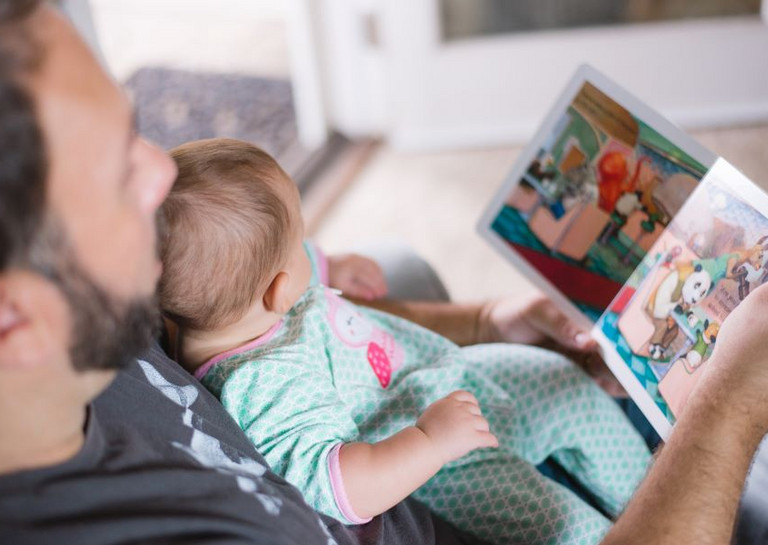 Mann liest Kleinkind aus einem Bilderbuch vor